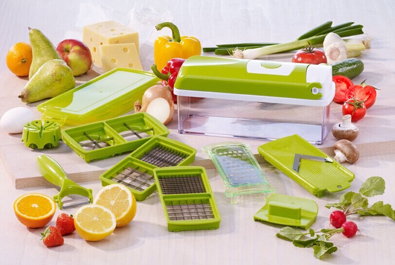 Set of green kitchen gadgets on a wooden surface with fruits and vegetables.