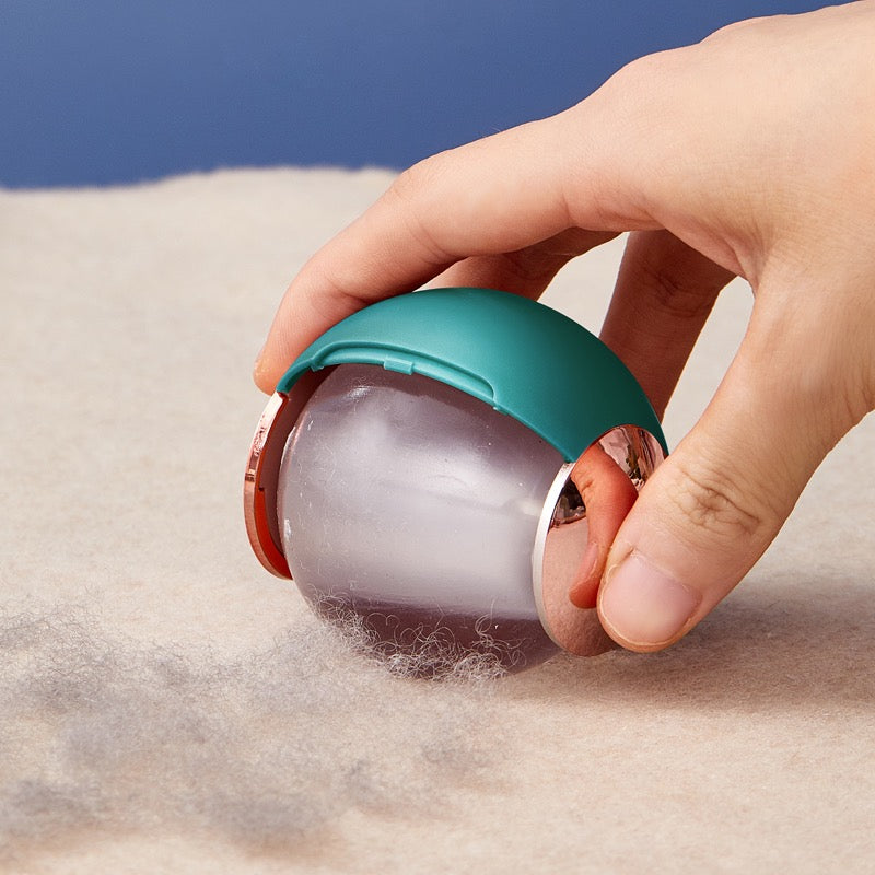 Hand using a pet hair removal tool on a carpet with a blue background