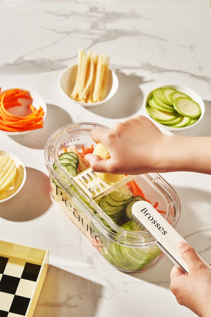 Person using a transparent container with a white lid to organize sliced vegetables on a marble surface.