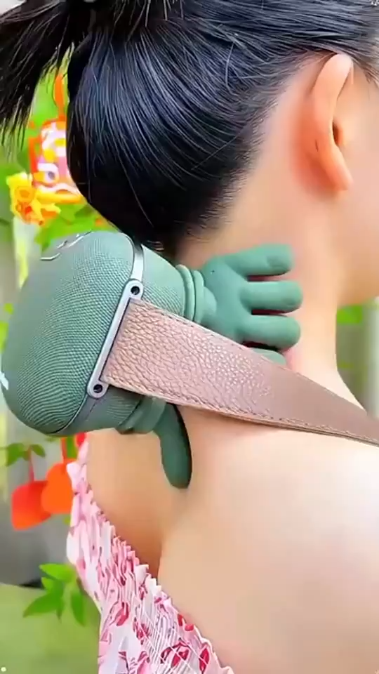 Person using a green neck and shoulder massager outdoors