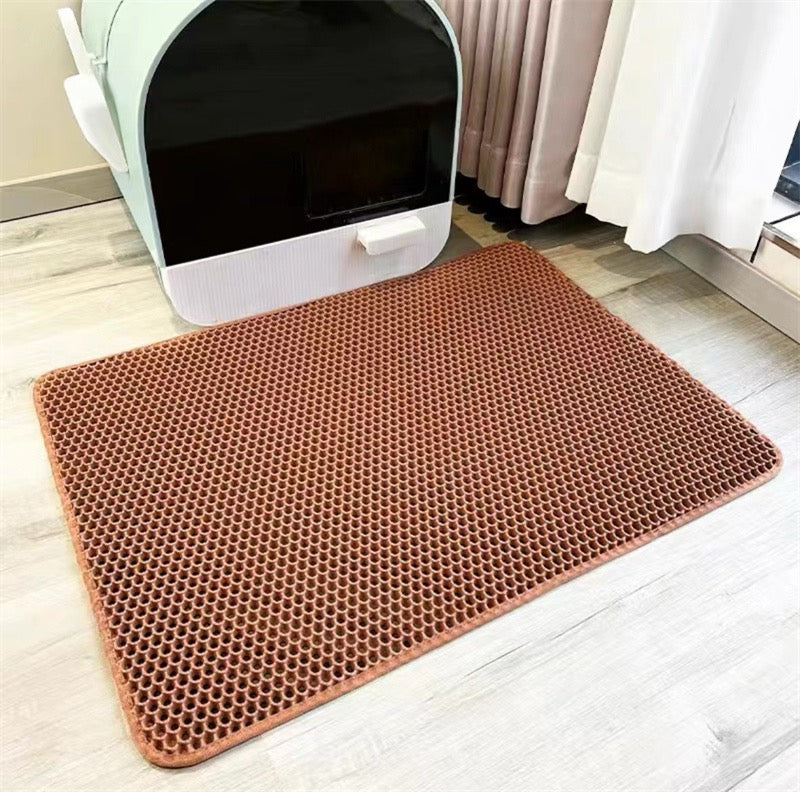 Brown honeycomb mat on a light wooden floor with a white pet litter box in the background.