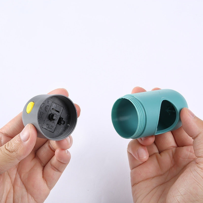Two small plastic components, one gray and one teal, held in hands against a white background.