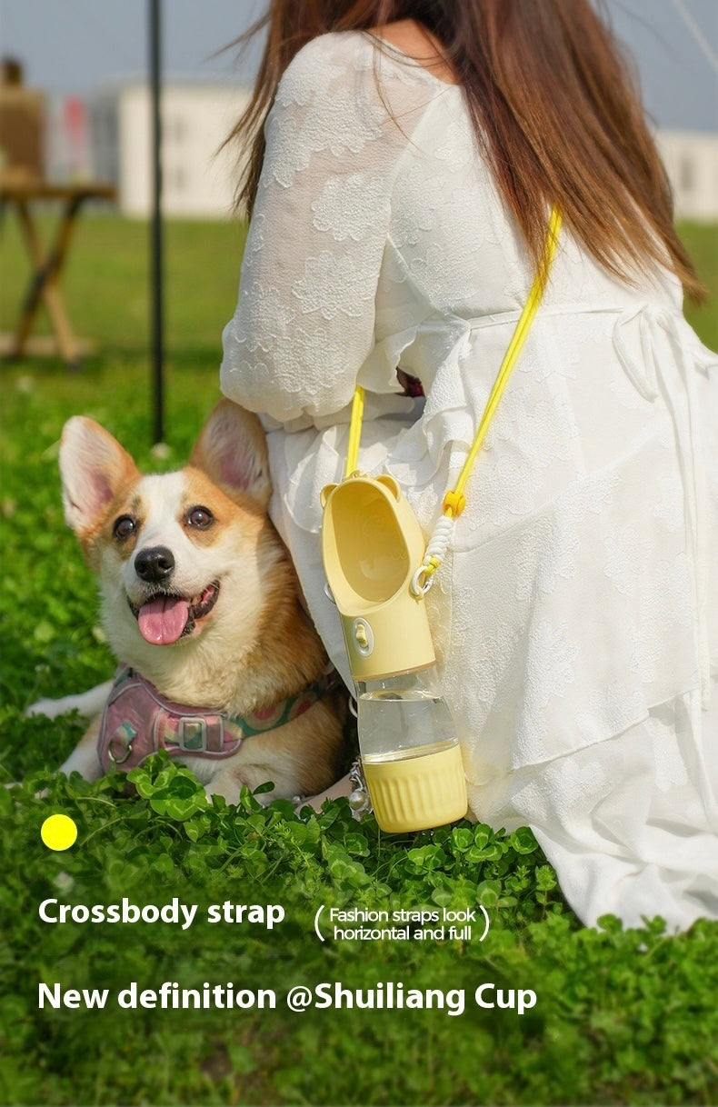 Woman in white dress with a dog and a yellow cup with a crossbody strap on grass