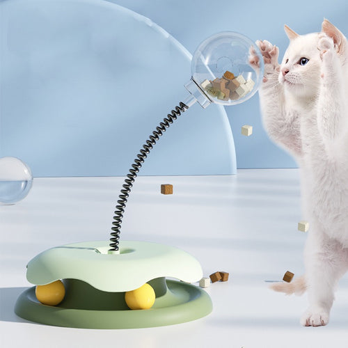 Cat playing with a green and yellow cat toy on a light blue background