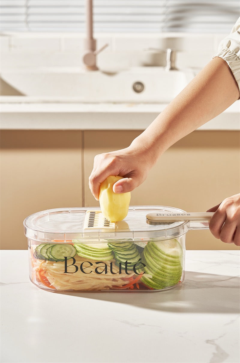 Person using a vegetable slicer with a container labeled 'Beaute' in a kitchen setting.