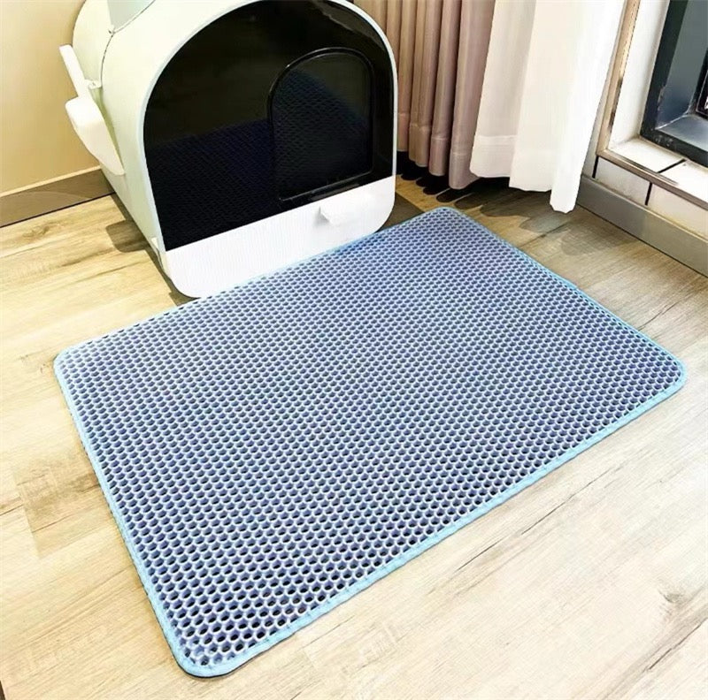 Blue mat with textured surface in front of a white pet litter box on a wooden floor.